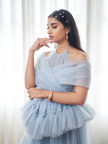 Introducing 'Diana', an enchanting powder blue halter-neck gown. It features a pleated corset-effect waist and cascading V-shaped ruffles on the skirt for a dramatic effect.