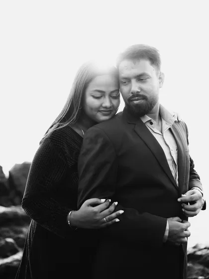 A beautiful black and white portrait against a bright, blown-out sky. The contrast creates a dramatic effect, focusing all the attention on the couple's gentle embrace and serene expressions.