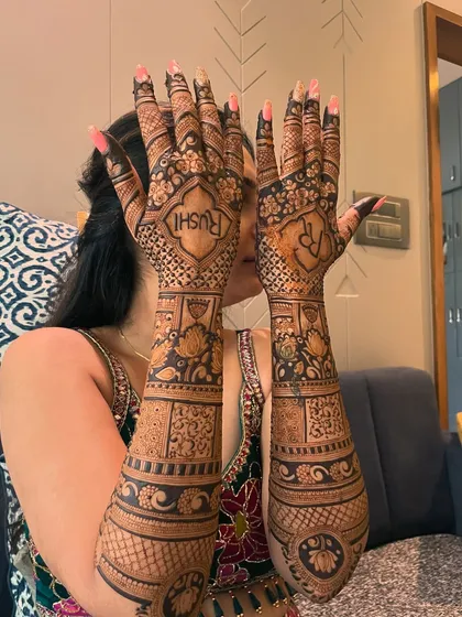 A personalized bridal mehendi for the back of the hands. This design features the groom's name "Rushi" and the couple's initials "RR" in a beautiful font.