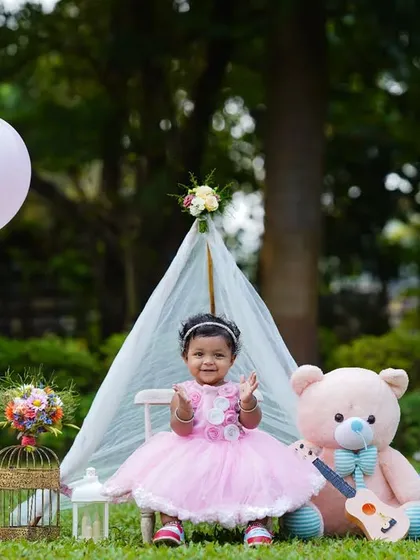 A complete first birthday setup outdoors, featuring a teepee, teddy bear, and festive props. This image showcases a full-concept outdoor birthday celebration shoot.