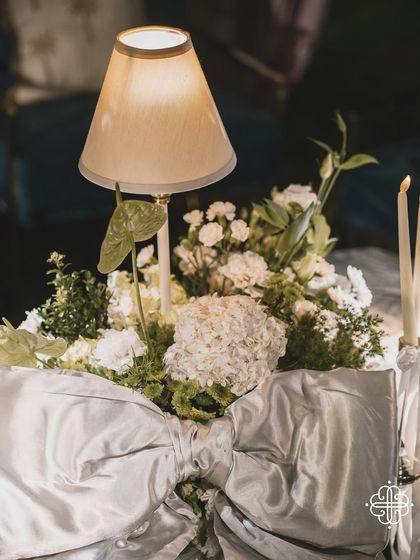 A close-up of a table lamp centerpiece with a large silver bow, part of the elegant decor for a Goa dinner party.