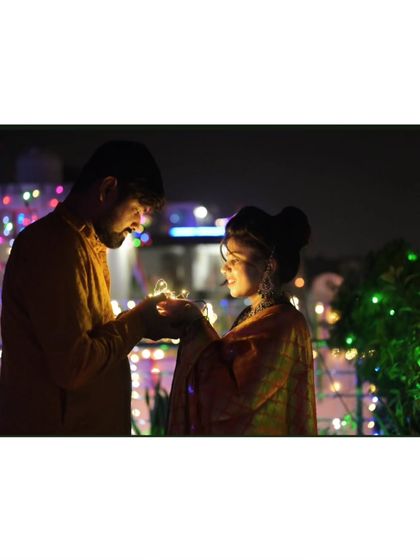 A romantic couple's photo for Diwali, holding fairy lights together against a backdrop of festive lights.