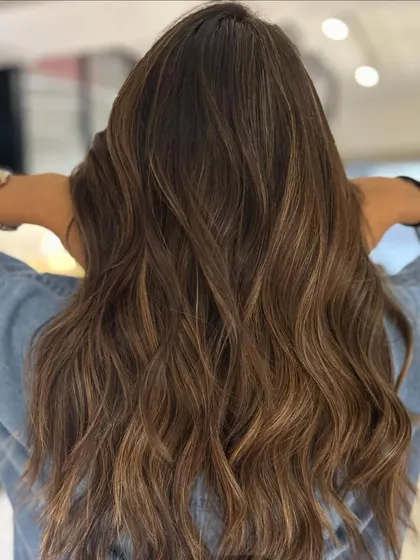 A sun-kissed beige balayage blend that's perfect for a beachy vibe. The textured layered haircut and waves complete this effortless, summery look.
