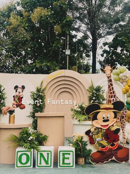 A closer look at the Mickey Mouse safari theme for Avyaan's first birthday. This view highlights the layered arch backdrop, the "ONE" letter blocks, and the placement of the explorer Mickey cutouts among floral arrangements.