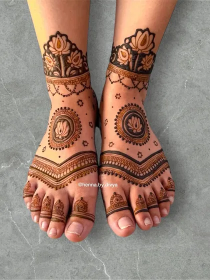 A clear and beautiful view of a lotus-themed foot mehendi. The design is perfectly symmetrical, with a central mandala, detailed toe work, and a matching floral anklet.