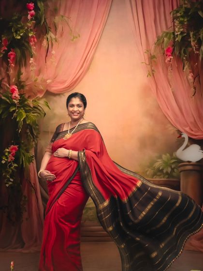 A dynamic portrait capturing the beautiful flow of the red saree against a romantic, painterly backdrop.