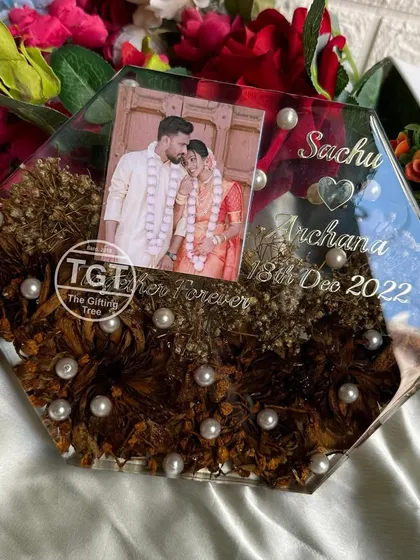 A unique 8-inch hexagonal tabletop frame preserving a one-year-old lotus varmala. The design includes a photo and custom text for a first-anniversary gift.