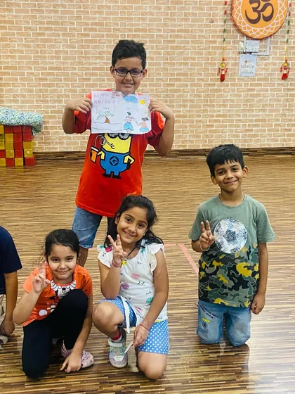 A group of happy kids showing off their drawings after an art class. The boy in the center is proudly displaying his colorful creation. Making art together is a great way to bond.