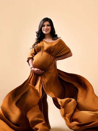 A moment of pure power and confidence. The rich, earthy brown of this flowing gown creates a dramatic effect, making the mom-to-be look like a goddess.