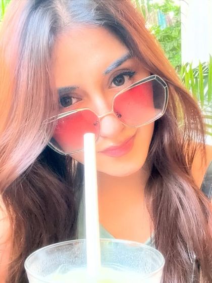 A close-up selfie with my matcha drink, wearing oversized pink sunglasses that add a fun pop of color.