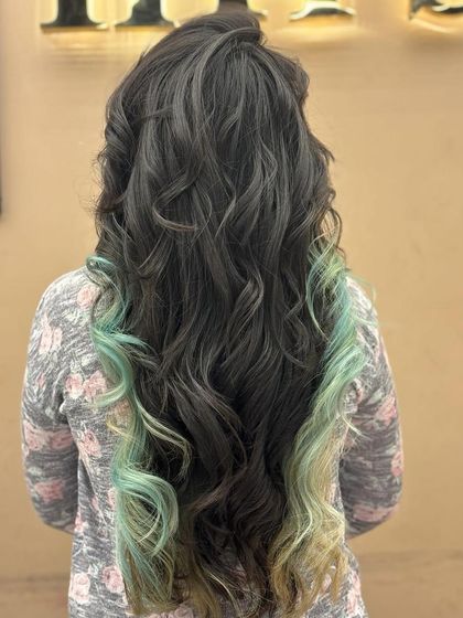 This back view shows a unique color combination of dark hair with mint green dip-dyed ends. The soft curls add a playful touch to this creative and eye-catching look.