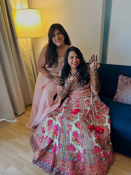 A sweet moment between sisters or friends, both showing off their unique party mehndi designs.