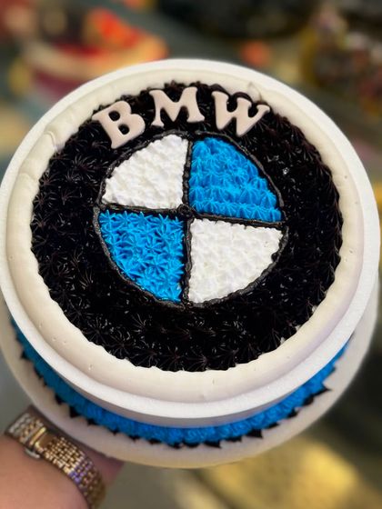 A classic BMW logo cake, meticulously crafted with buttercream piping. The iconic blue, white, and black colors are sharp and clean, making it a great choice for a BMW enthusiast's birthday.