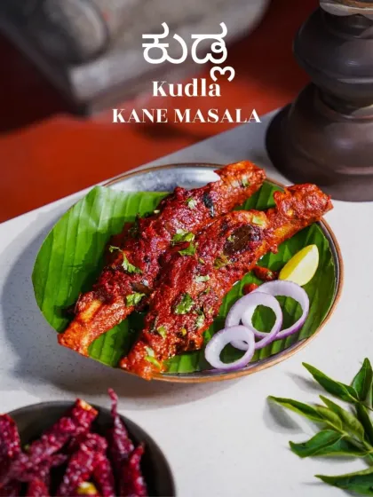 Kudla Kane Masala, a fiery fish preparation from Mangalore, served on a banana leaf. The deep red of the masala and the fresh garnish make this dish look incredibly flavorful and authentic.