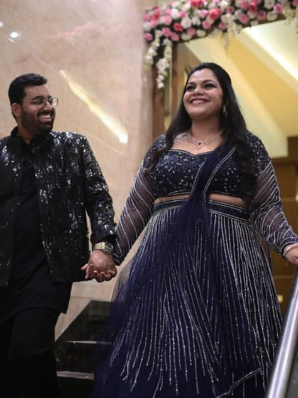 A happy moment captured as the couple descends the stairs. The bride's glamorous makeup and radiant smile light up the frame.