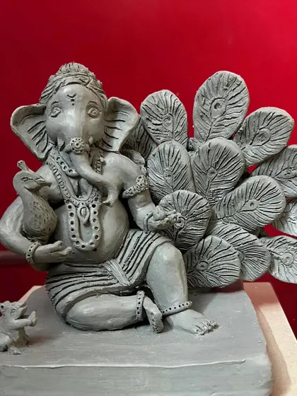 This custom 'Mayur Pankh' Ganesha is one of my favorite commissions. I sculpted each peacock feather individually from Shadu clay to create a detailed backdrop for Bappa, who holds a small peacock. The entire idol is unpainted, highlighting the natural, earthy texture of the eco-friendly clay.
