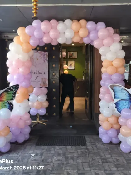 A grand entrance for a butterfly-themed party, with a pastel balloon arch flanked by large, colorful butterfly cutouts.