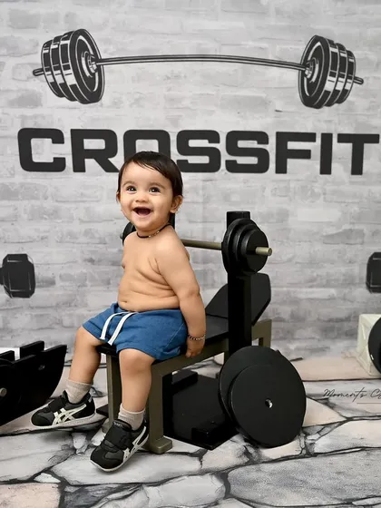 A huge smile from our little gym enthusiast. His pure joy is evident as he sits on the bench, surrounded by his tiny workout equipment.