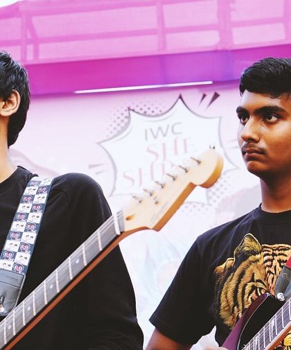 Two of our guitarists, focused and ready to rock during a live show. Playing together in a band teaches teamwork and musical communication.