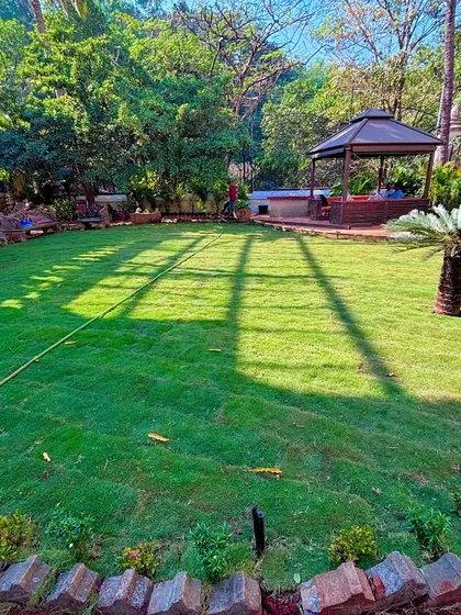 A wide view of a finished residential garden, complete with a perfectly installed lawn, a brick border, and a gazebo area in the background. This is the kind of beautiful, functional outdoor living space I love to create.