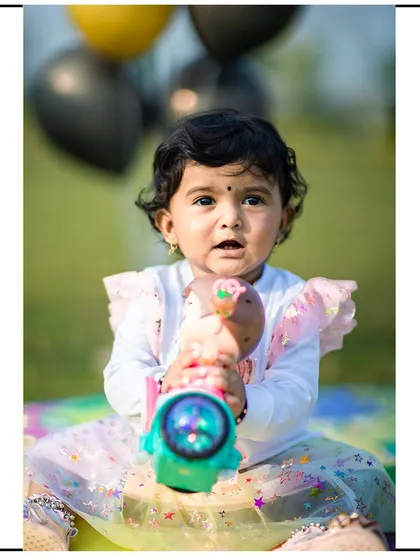 A direct and engaging portrait of a little girl with her toy. The blurred green background keeps the focus entirely on her.