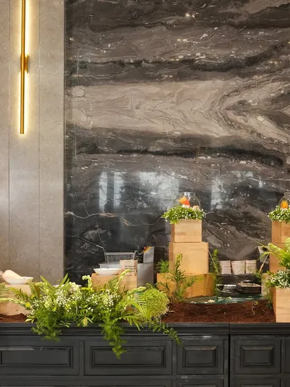 A modern and minimalist buffet setup using wooden blocks and fresh greenery for elevation and decor. This clean aesthetic allows the food to be the star of the show.