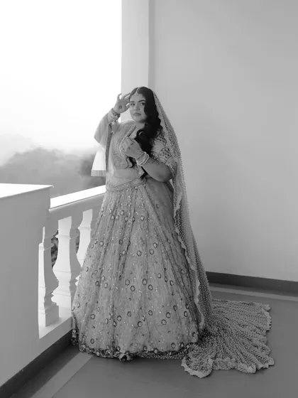 A striking black and white full-length portrait of the bride on a balcony, with a misty mountain view in the background.