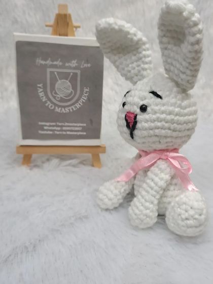 A small, 6-inch white bunny in a sitting position, tied with a pink ribbon.