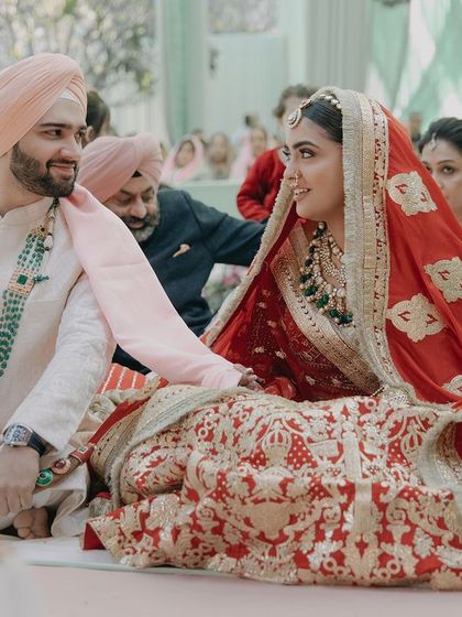 A candid shot of Anmol and Ashmeet during their Anand Karaj ceremony. The image captures a quiet, meaningful glance between the couple amidst the sacred rituals.