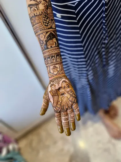 A side view showing how the family portrait on the palm connects with the traditional patterns flowing up the arm, creating a cohesive and meaningful bridal design.