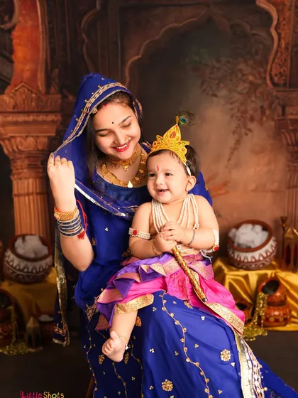 Celebrating festivals with little ones is so special. Here, an older sister lovingly holds her baby sibling, both dressed for a Janmashtami themed photoshoot. I use detailed backdrops and traditional costumes to bring these festive concepts to life.