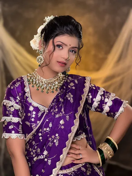 A full view of the regal purple saree look. The makeup is designed to balance the rich color of the outfit and the heavy jewelry, ensuring the bride's natural features shine through.