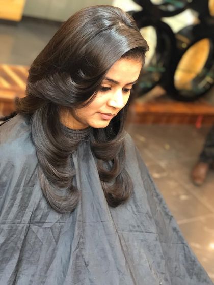 A classic blowout on medium-length hair. This styling technique creates volume at the roots and soft, inward-curled ends for a polished look.