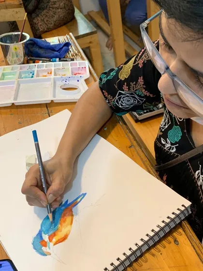 A student adds details to a kingfisher painting with colored pencils over a watercolor base. We also explore mixed media techniques in our advanced classes.