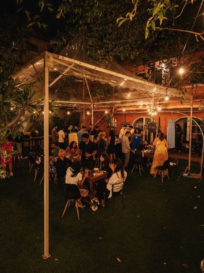 A scenic outdoor event at night, with string lights creating a magical canopy over the garden party.