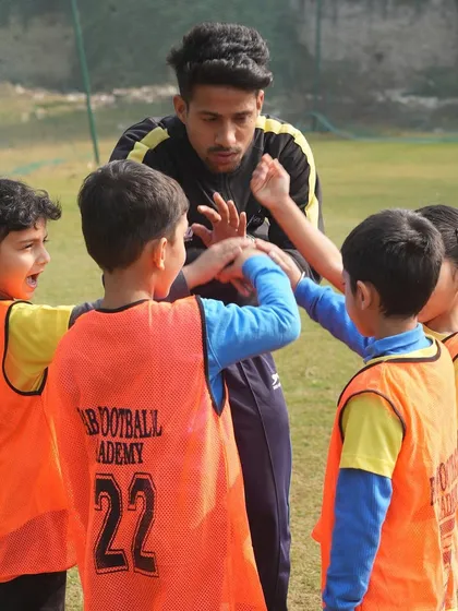 A coach and players in a huddle. We instill values like discipline and teamwork from a tender age.