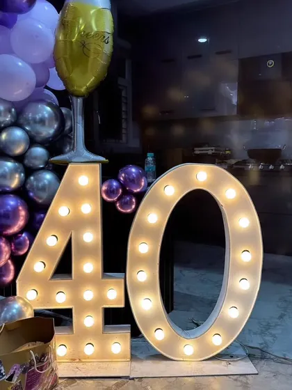 I provide large, light-up marquee numbers for milestone birthdays. Here is a '40' used for a birthday party, placed next to a purple and silver balloon arrangement.
