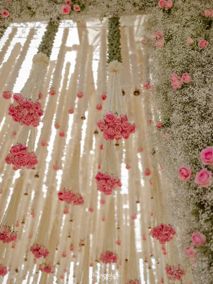 Looking up into the floral canopy, this shot reveals the delicate arrangement of hanging flower strings and rose bunches, creating a dreamlike ceiling.