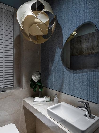 It’s all about the details. This powder room features a sculptural pendant light that acts as a piece of art, casting beautiful shadows on the blue mosaic-tiled wall. The organic-shaped mirror adds another layer of artistic flair.