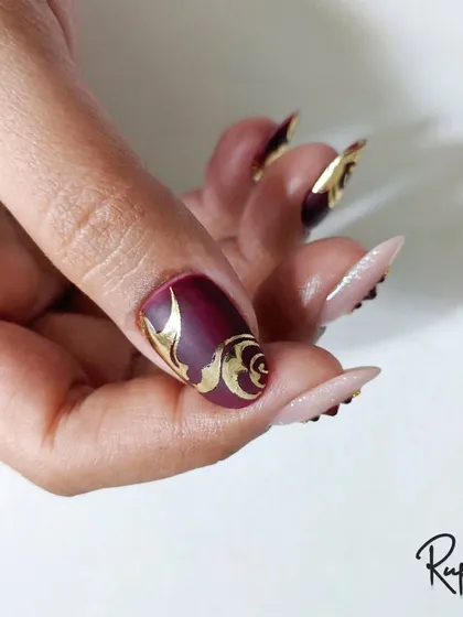 A photo of the foil and swirl design on a full set of stiletto nails.