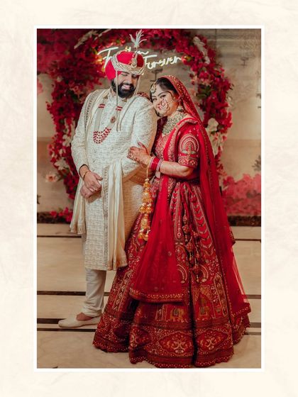 A beautiful portrait of the couple in front of a red floral arch with a 'Forever' neon sign, a perfect backdrop for their love story.