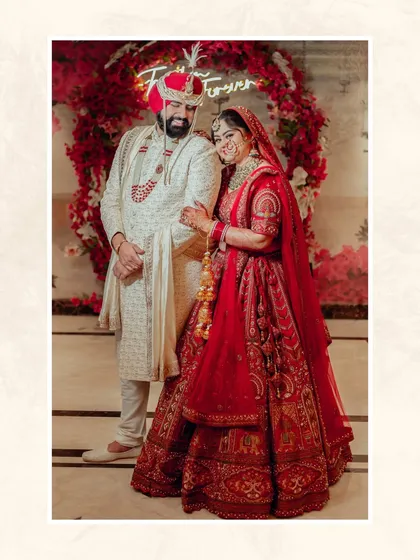 A beautiful portrait of the couple in front of a red floral arch with a 'Forever' neon sign, a perfect backdrop for their love story.