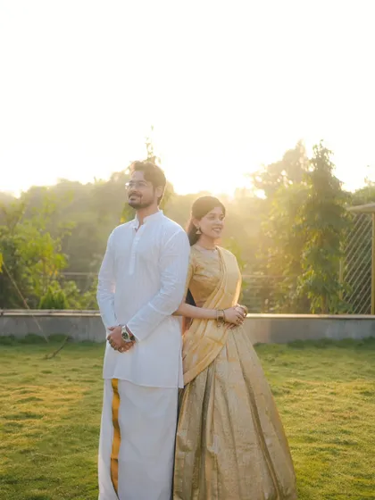 A couple in traditional South Indian attire stands back-to-back against a golden sunset. This pose is both playful and stylish, creating a beautiful pre-wedding portrait.