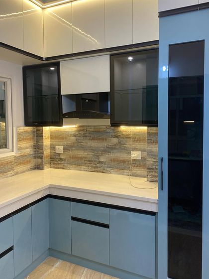 A closer look at the blue and white kitchen, focusing on the black-framed glass cabinets and the textured backsplash.