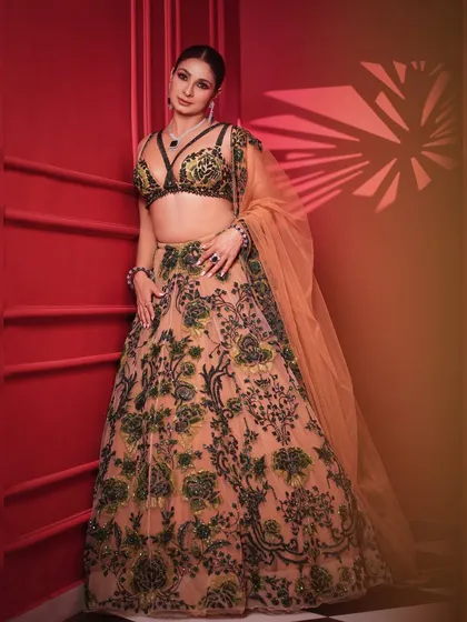 A three-quarter shot that highlights the modern design and beautiful craftsmanship of the lehenga. The lighting creates a dramatic effect, perfect for an editorial feature.