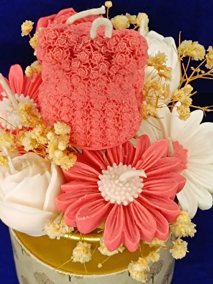 A close-up of a candle bouquet featuring a rose-textured teddy bear.