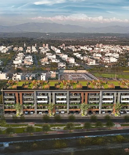 An aerial view of Gulnaar Lifestyle, showcasing its green rooftop and its placement within the larger cityscape, with mountains in the distance.