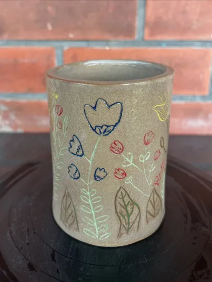 A lovely tumbler decorated with delicate, colorful floral illustrations. This piece was made by a student in a combined hand-building and wheel course.
