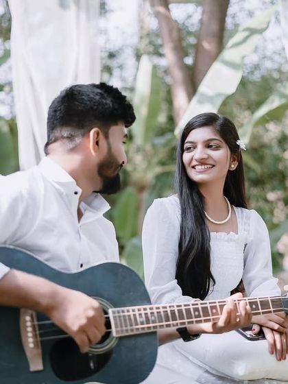 A close-up of the couple during their romantic picnic. The groom-to-be plays the guitar, and his partner's loving gaze says it all.