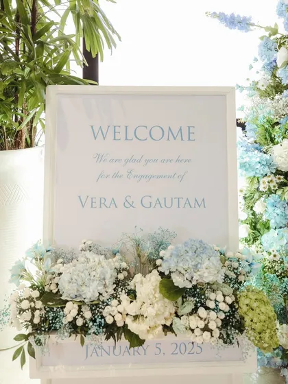The personalized welcome sign for Vera & Gautam's engagement, nestled in a bed of blue and white hydrangeas, creating a beautiful and heartfelt first impression.